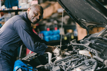 Fototapeta na wymiar happy smiling mechanic male car engine service underhood checking oil replace in broken part at auto garage