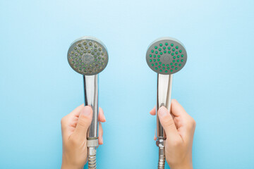 Woman hands holding new and old shower heads on light blue table background. Pastel color. Compare...