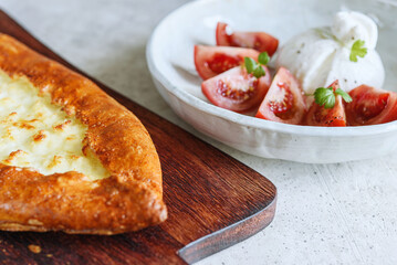 Traditional Turkish baked pide dish. Middle Eastern snacks. Turkish pizza. Turkish pide with cheese - Kasarli Pide and tomatoes with burrata cheese on grey concrete background. Selective focus - 536136431
