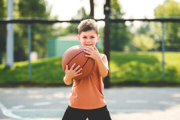 portrait of a boy kid playing with a basketball in park