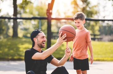 man and young boy playing basketball on a court, teaching little player and spending time outdoors