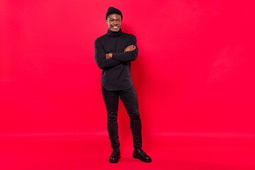 Full length body size view of attractive cheerful guy folded arms wearing black garment isolated over bright red color background