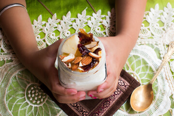 Healthy Indian breakfast cereal in hand containing Flattened rice, curd, fruit, nut. Yummy and...