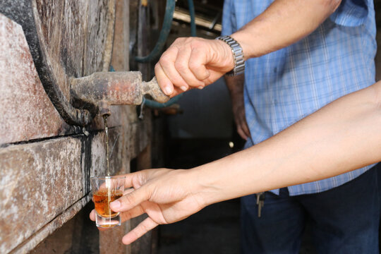 hand opening wooden barrel pouring alcohol into a small glass. Brazilian export beverage. Brazilian product for export, distilled beverage known as cognac, pinga or cacha&ccedil;a