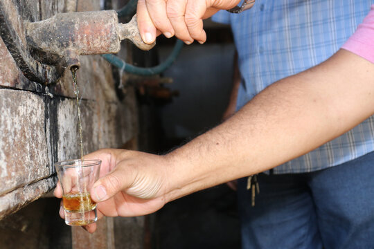 hand opening wooden barrel pouring alcohol into a small glass. Brazilian export beverage. Brazilian product for export, distilled beverage known as cognac, pinga or cacha&ccedil;a