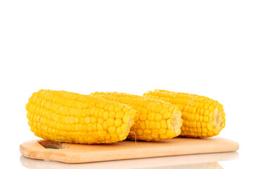 Three fragrant boiled corn on a wooden cutting board, macro, isolated on white background.