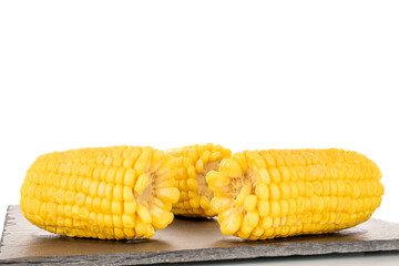 Three fragrant boiled corn on a slate stone, macro, isolated on a white background.