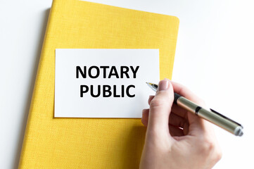 a woman in a white shirt holds a piece of paper with the text: notary public. business concept for companies