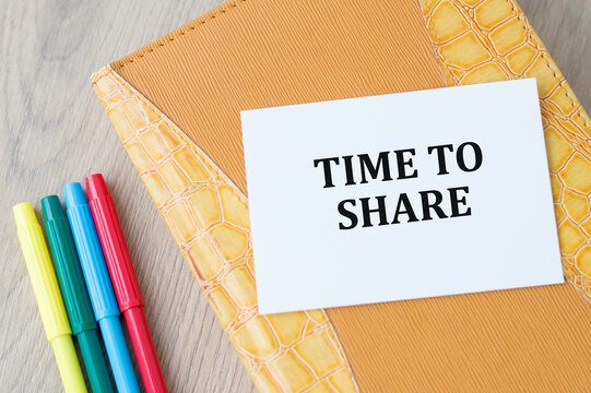 Time to Share text on a card that sits on a notebook on a wooden table