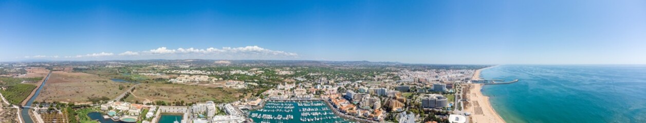 Fototapeta na wymiar Sensational panorama of beautiful Vilamoura city. Luxury hotels, yachts docked in the port. Famous travel destination in south of Portugal - Algarve region. View of the city and the port area