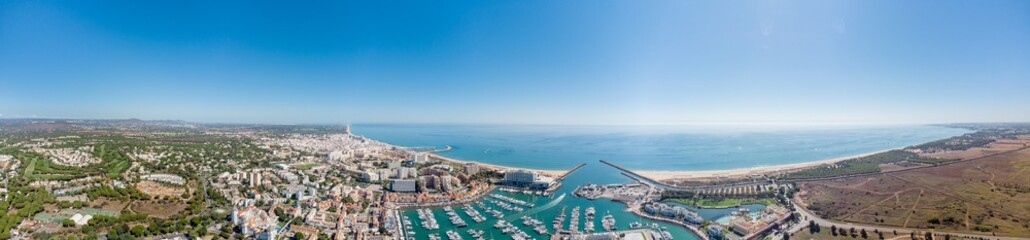Fototapeta na wymiar Sensational panorama of beautiful Vilamoura city. Luxury hotels, yachts docked in the port. Famous travel destination in south of Portugal - Algarve region. View of the city and the port area