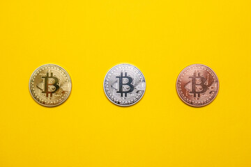 Bitcoin BTC gold, silver and bronze coins on a yellow background. Decentralized blockchain...