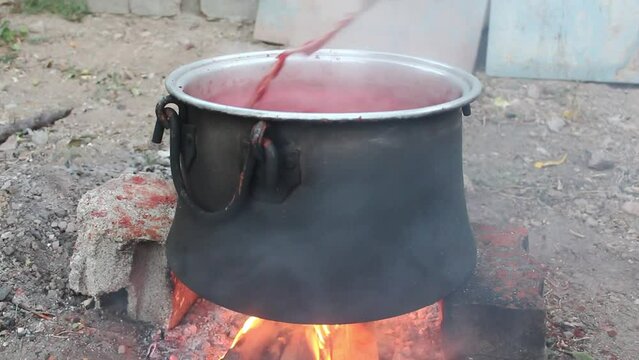 Tomatoes boiled in a cauldron on a hot fire turn into tomato paste.