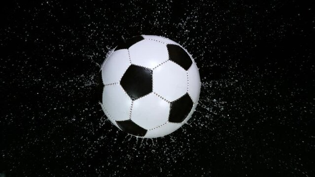 Close-up of Falling Soccer Ball on Water Black Surface. Super Slow Motion at 1000 fps. Filmed on High Speed Cinematic Camera.