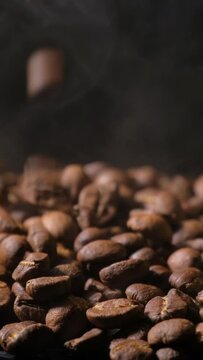 Vertical slow motion of roasted coffee beans falling. Organic coffee seeds.	