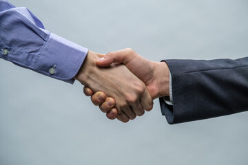Businessmen in office clothes standing and shaking hands, close-up. Business communication concept. Handshake, cooperation, partnership