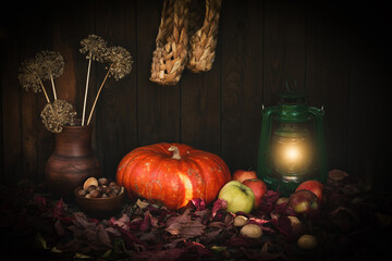 Autumn authentic rustic set on wooden backdrop with pumpkin, paraffin lamp, nuts, apples, clay jug...