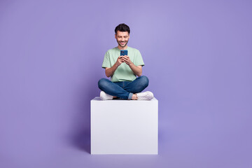 Full body photo of attractive young guy hold gadget sit white cube apple samsung wear trendy gray...