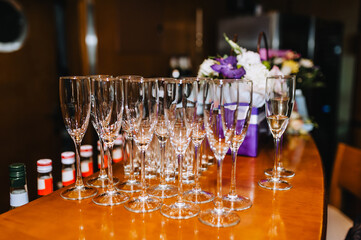 A lot, a row of empty transparent expensive wine glasses stands on a wooden table in a bar, cafe close-up.