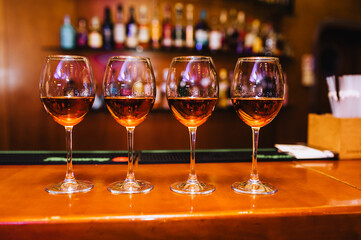 Wine glass goblets with alcoholic cocktails stand on a wooden table in a bar.