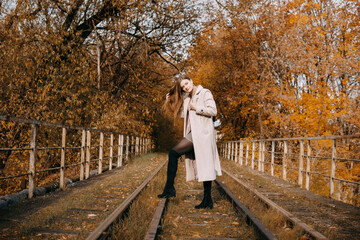 beautiful long-haired woman walks through the autumn streets. Railway, autumn, woman in a coat.