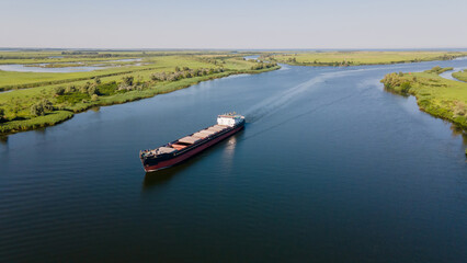 Grain carrier in the sea goes along the Dnieper. Delivery of wheat worldwide. Ship logistics in Ukraine.