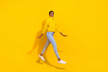 Full length body size view of attractive cheerful trendy slender skinny girl jumping going isolated over bright yellow color background