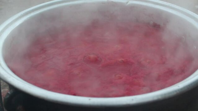 Tomatoes boiled in a cauldron on a hot fire turn into tomato paste.