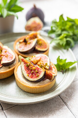 Delicious tartlet with crispy almond-flavored pastry, delicate cheese cream and fresh figs, grey tilled background. Autumn dessert. National Dessert Day, October 14.