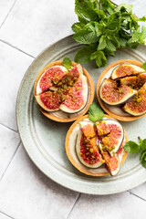 Delicious tartlet with crispy almond-flavored pastry, delicate cheese cream and fresh figs, grey tilled background. Autumn dessert. National Dessert Day, October 14.