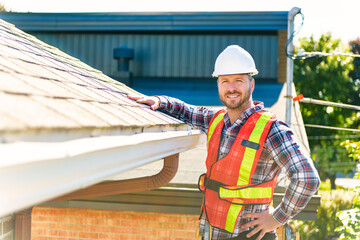 man with hard hat standing on steps inspecting house roof © Louis-Paul Photo