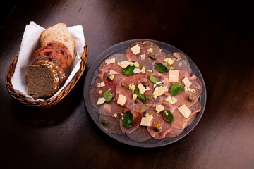 romantic dinner with carpaccio catfish deli meat basket of artisan breads caper mustard dijon top view