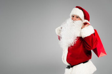 Bearded santa claus in costume holding shopping bag isolated on grey.