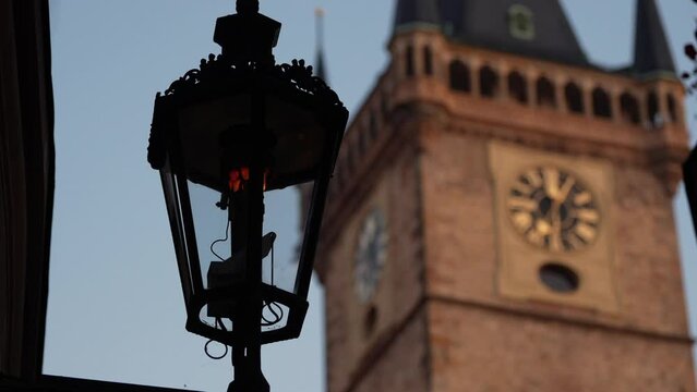 4K video with Old Town Clock Tower in Prague during a beautiful autumn sunrise with vintage street light bulb turning off in foreground. Landmarks of Czech Republic.