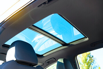 Automobile panoramic glass roof in a modern car. Blue sky view.