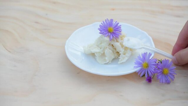 unrefined shea butter, a natural moisturizing cosmetic, 
with purple flowers