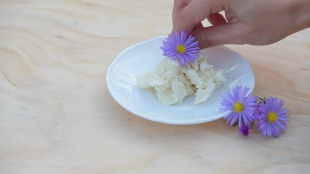 unrefined shea butter, a natural moisturizing cosmetic, 
with purple flowers
