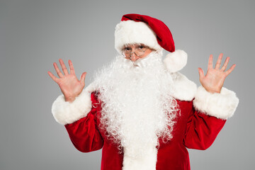 Santa claus in eyeglasses and costume waving hands isolated on grey.