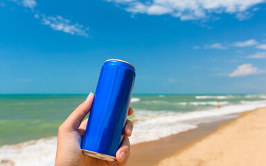 A jar with a cold drink in hand against the backdrop of the sea shore. Close-up.