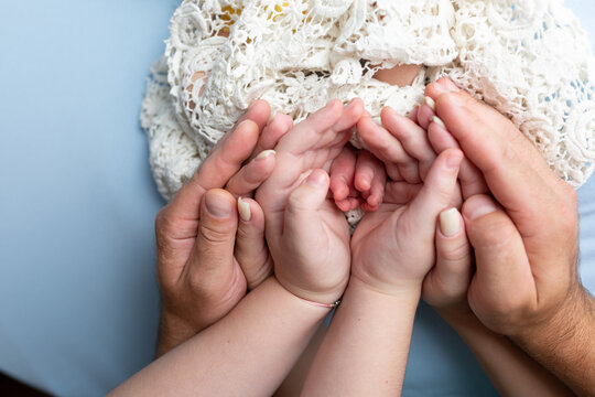 legs of the child in the arms of parents and older brother. family hands