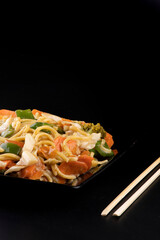chinese food delivery black vegetarian yakisoba black plate with chopsticks close-up portrait