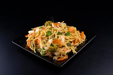 chinese food delivery black plate of yakisoba vegetarian black wide angle portrait