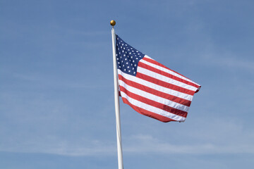 American flag waving in the wind with a blue sky