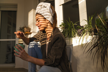 Beautiful woman drinking tea enjoying sun on her balcony