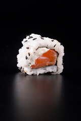 japanese oriental food was just a piece of raw salmon sushi with cream cheese and sesame isolated on black background viewed from the front