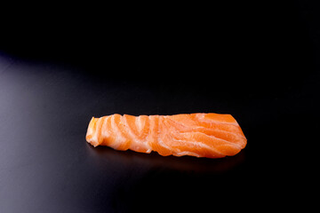 one piece of raw salmon sashimi japanese food isolated on black background angle view delivery