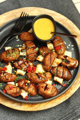Appetizing juicy grilled mushrooms on a dark plate with spices. Macro.