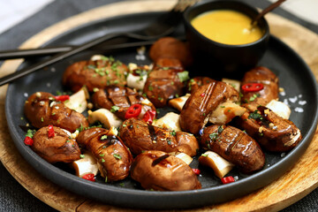 Appetizing juicy grilled mushrooms on a dark plate with spices. Macro.