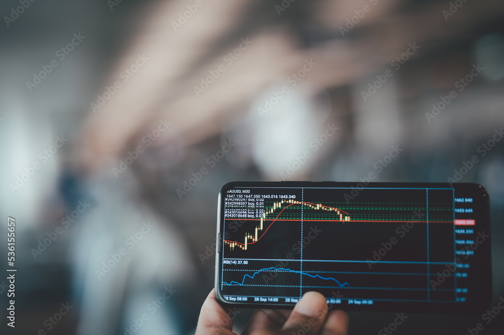 Poster close-up shot of smartphone during the man is using stock market app to check share prices and seein