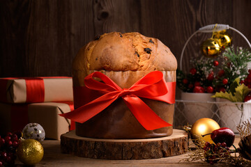 Traditional Italian Christmas Cake Panettone with red bow and festive decoration on wooden rustic...